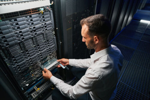 A back image of a professional it specialist working in data center maintaining the on-premise server structure.