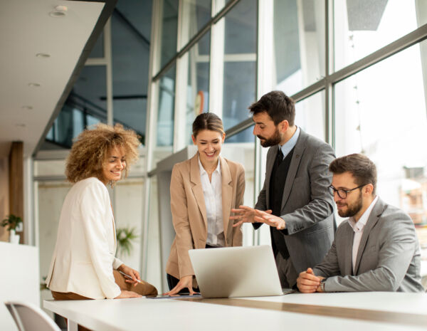 A team of four people in a modern light office discussing print management strategies.