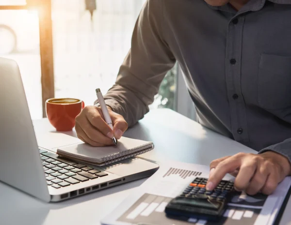 Man werkt aan zijn financiën met behulp van een laptop en rekenmachine.